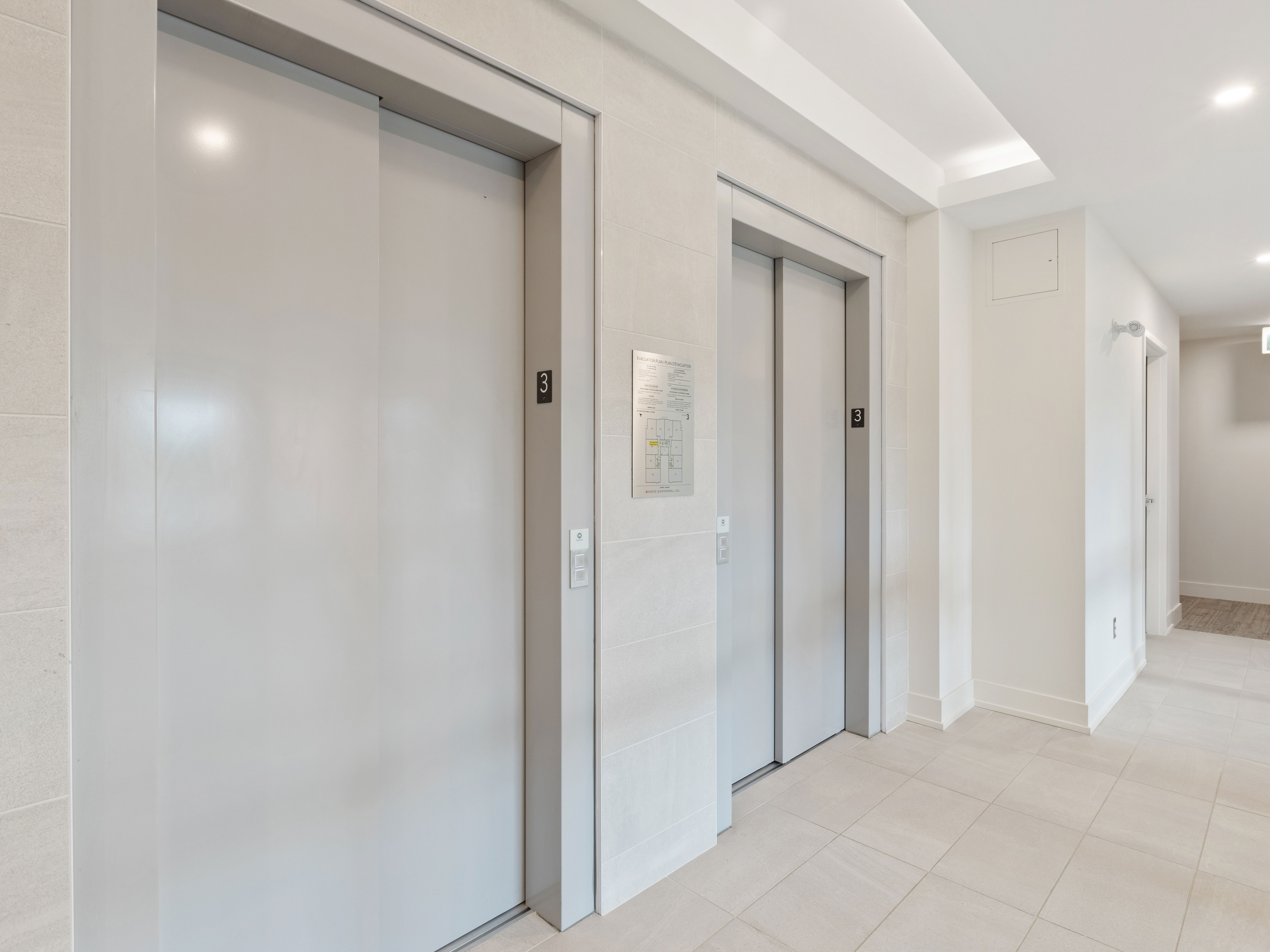 Two Rosh Elevators doors on a floor with 3 written on the wall.