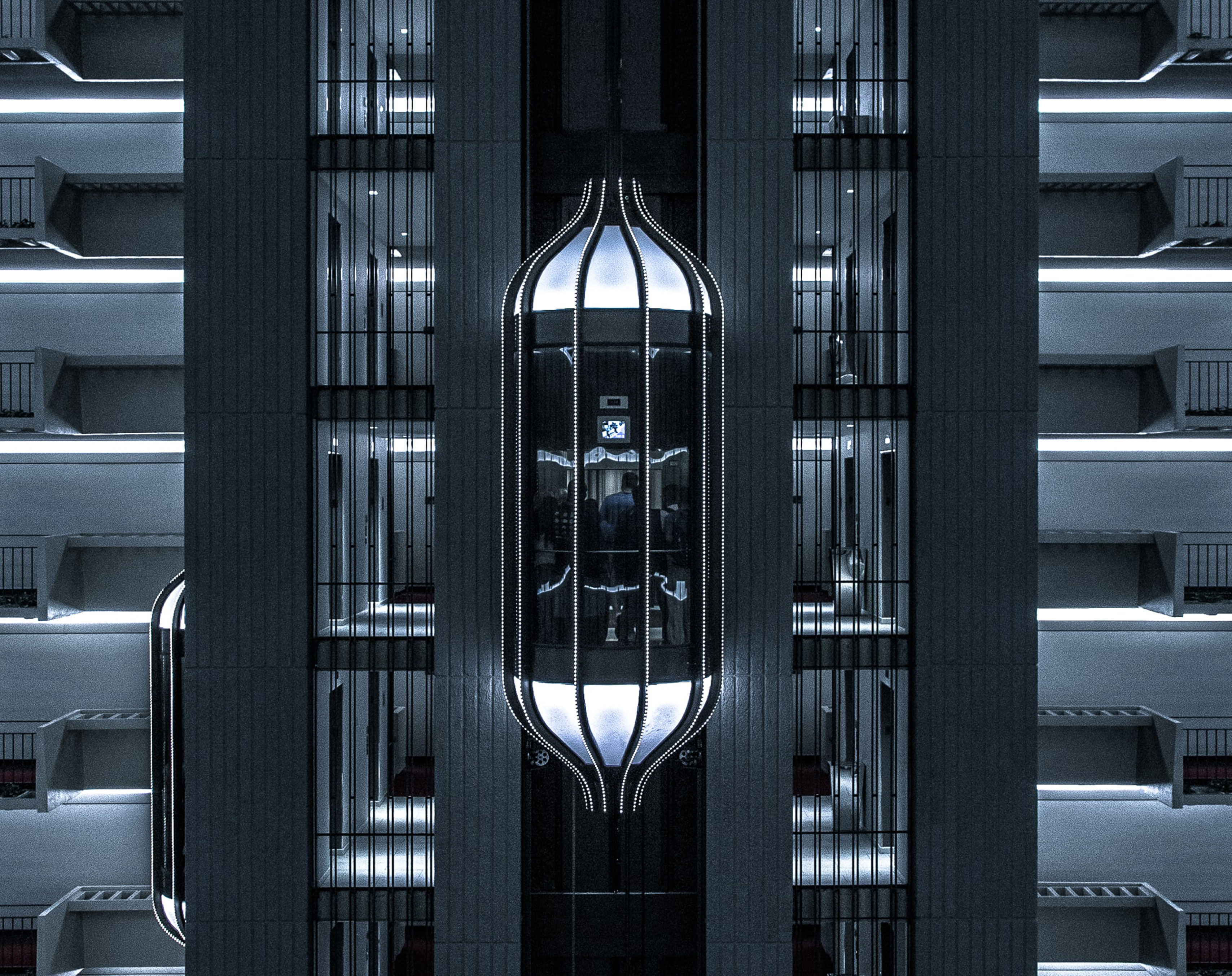 Rosh Elevators lift in the center of the many floors and its in working position and some people are inside the lift.